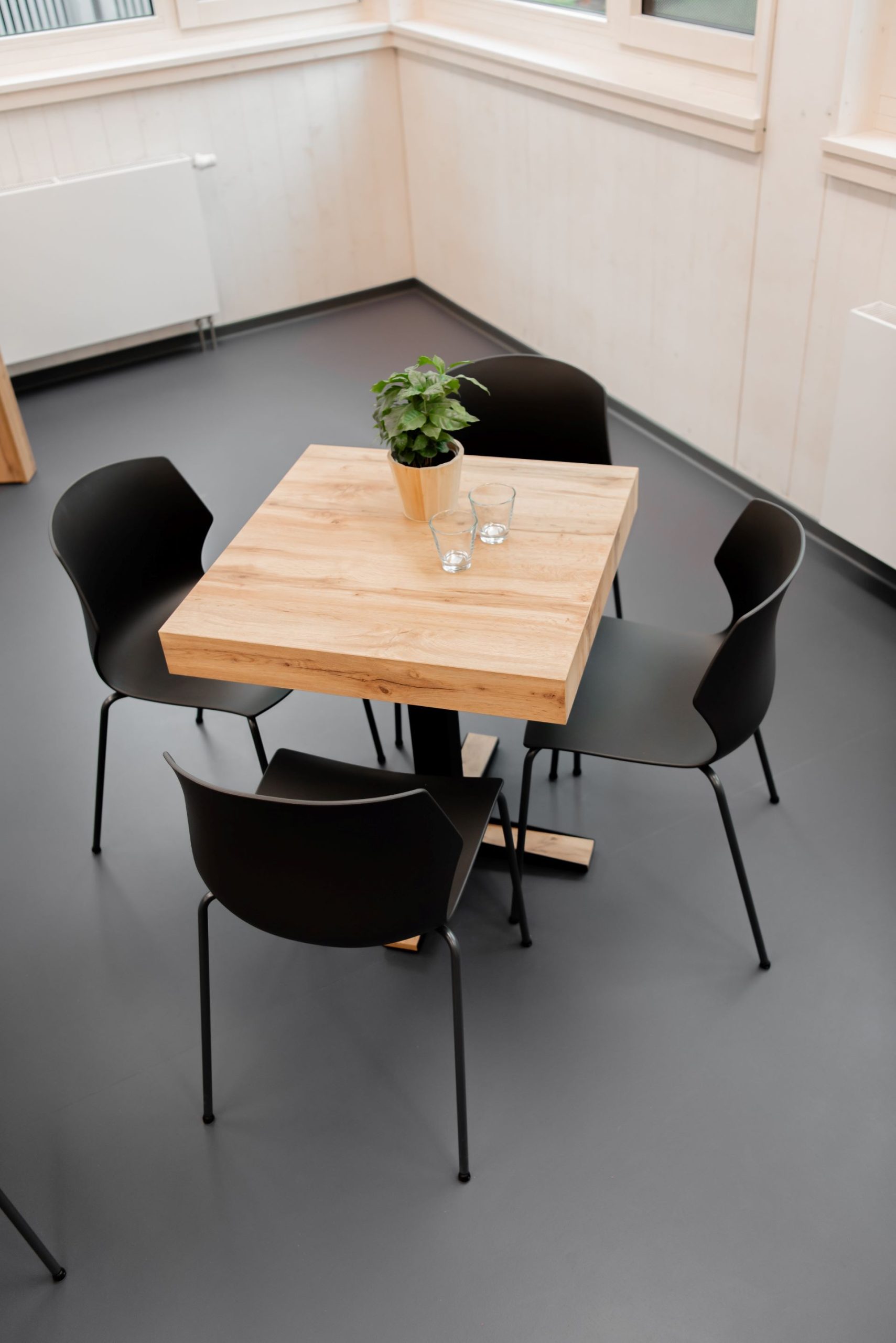 Een vierkante houten tafel met vier zwarte stoelen