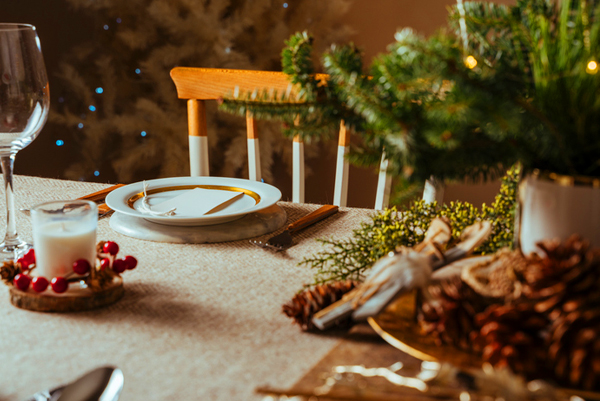 Lege gele stoel aan een gedekte kersttafel met mini kerstboom